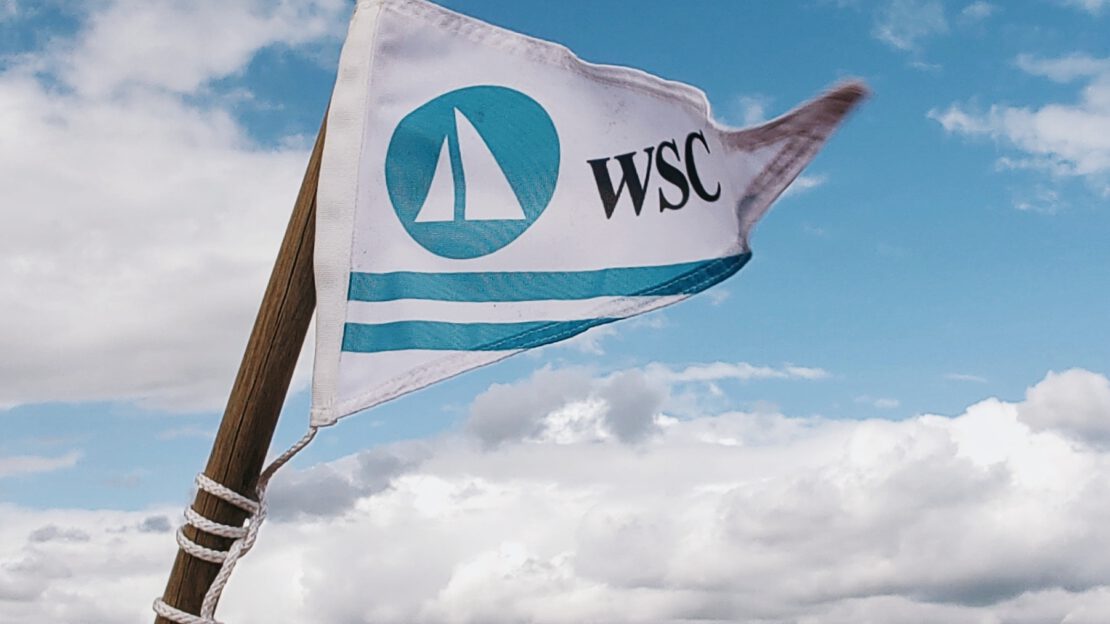 Wimpel mit WSC-Logo vor dem Wandlitzsee mit Segelbooten im Hinteregrund